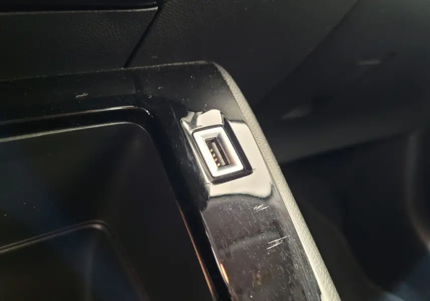 Gros plan sur un port USB intégré dans la console centrale noire d'un Peugeot 208 gris foncé 2023.