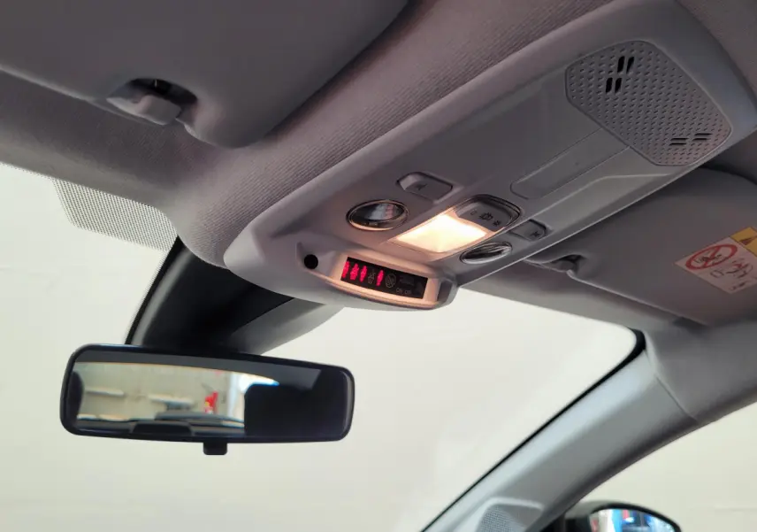 Vue intérieure du plafonnier et rétroviseur central d'une Peugeot 208 gris foncé, avec éclairage allumé.