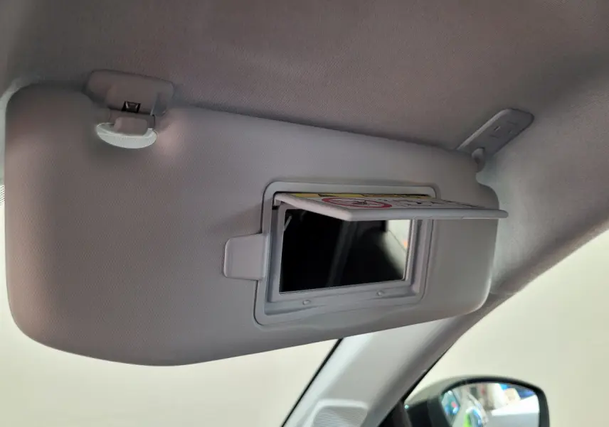 Miroir de courtoisie ouvert sur pare-soleil côté conducteur dans l'habitacle gris clair d'une Peugeot 208 2023.
