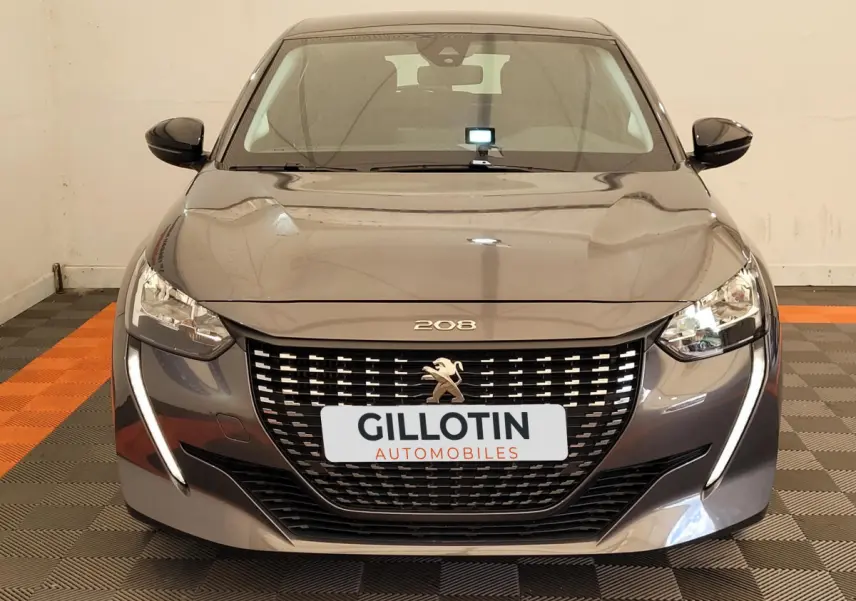 Vue frontale d'une Peugeot 208 gris foncé avec calandre noire et feux LED en forme de griffes.