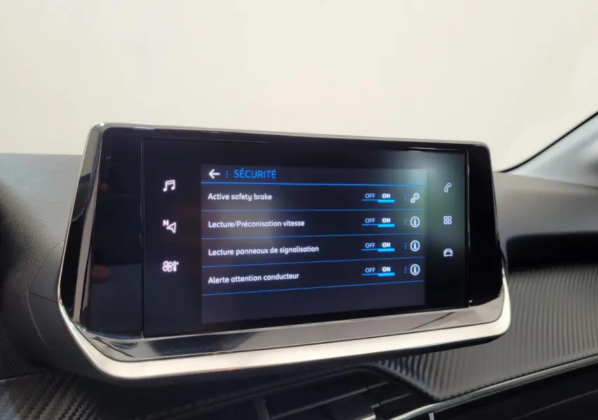 Écran tactile central affichant les réglages de sécurité dans l'habitacle d'une Peugeot 208 gris foncé.