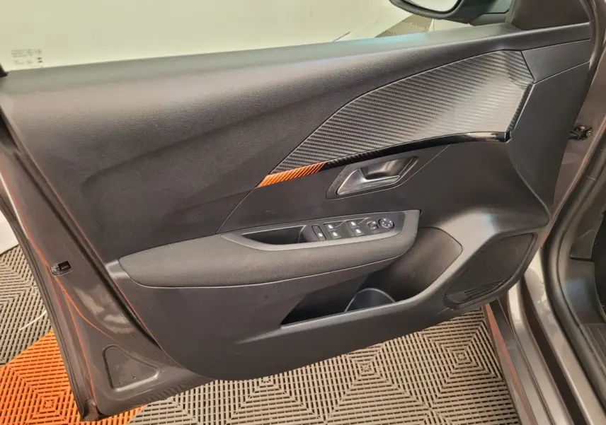 Vue intérieure côté gauche de la porte avant gris foncé de la Peugeot 208 avec inserts noirs et commandes électriques.
