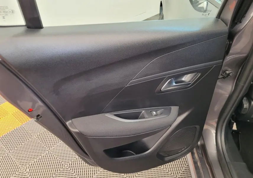 Gros plan sur la porte arrière droite gris foncé de la Peugeot 208 BlueHDi 100 S&S Active Pack avec commande de vitre et haut-parleur intégré.