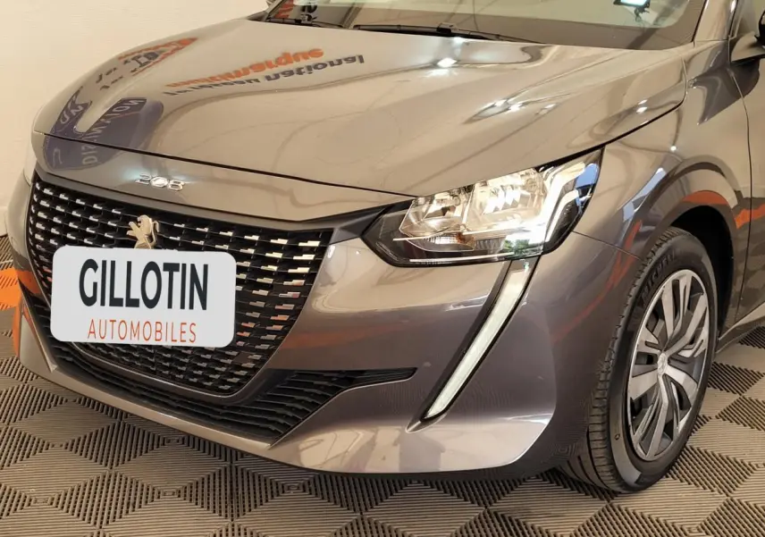 Vue 3/4 avant droit d'une Peugeot 208 gris foncé avec calandre distinctive et phares LED en forme de griffes.