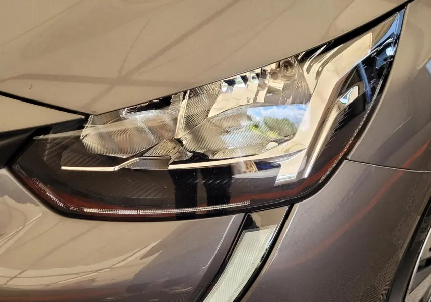 Gros plan sur le phare avant droit gris foncé de la Peugeot 208 BlueHDi 100 S&S Active Pack 2023.