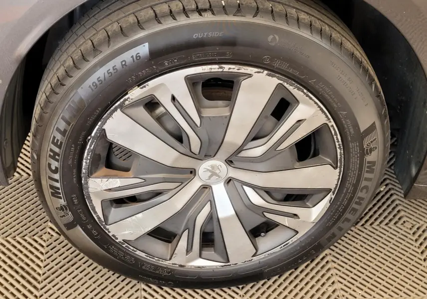 Gros plan sur la roue avant droite d'une Peugeot 208 gris foncé avec jante alliage au design moderne.