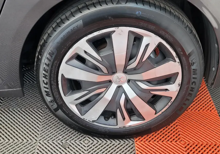 Gros plan sur la roue avant droite d'une Peugeot 208 gris foncé avec jante en alliage et pneu Michelin.
