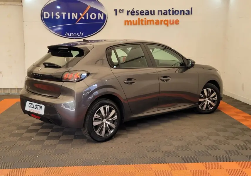 Peugeot 208 gris foncé vue 3/4 arrière droit en intérieur avec jantes alliage et feux LED distinctifs.