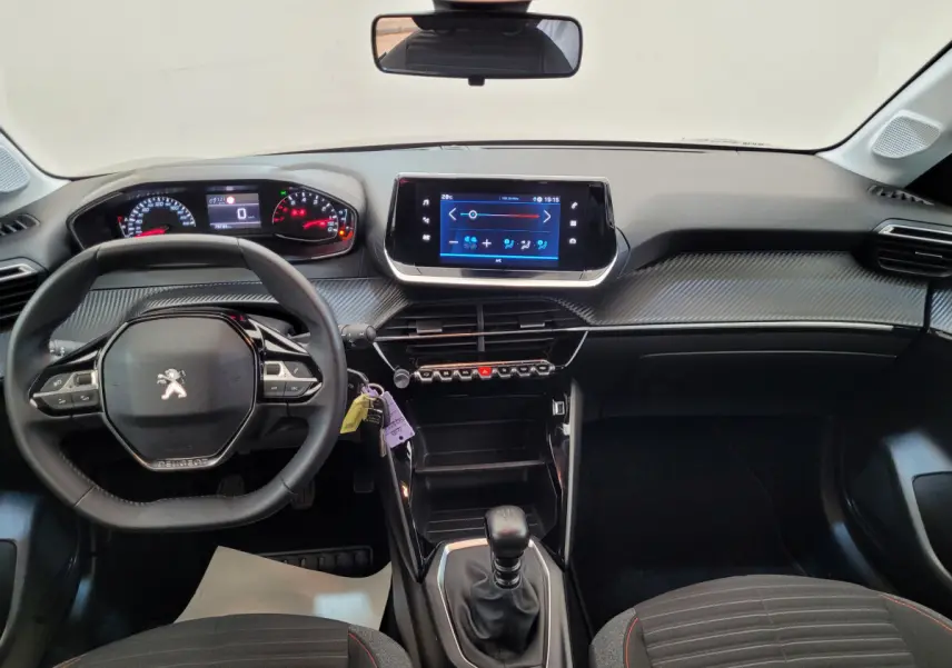 Vue intérieure avant du tableau de bord et volant cuir noir de la Peugeot 208 gris foncé avec écran tactile central.