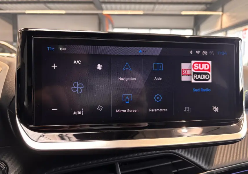 Écran tactile central du tableau de bord du Peugeot 2008 gris, affichant les options de navigation et climatisation.