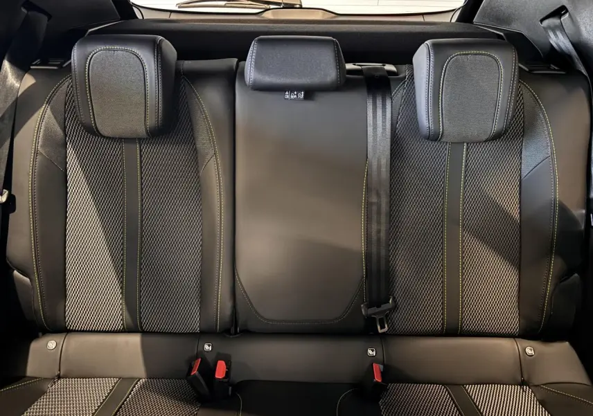 Vue intérieure arrière des sièges noirs avec surpiqûres vertes du Peugeot 2008 gris hybride 2025 GT Phase 2.