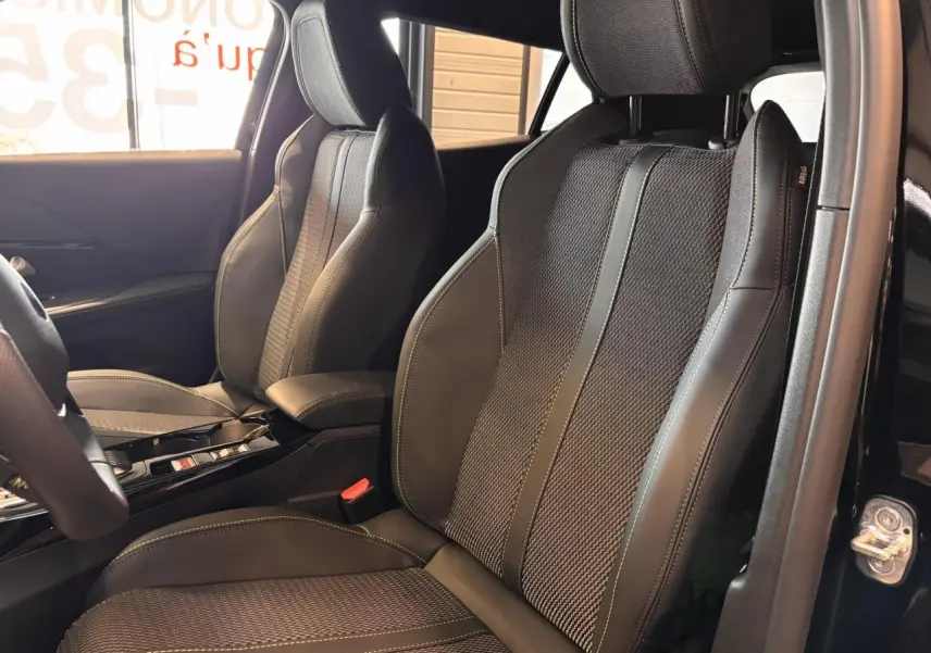 Vue rapprochée des sièges avant en cuir noir et tissu gris avec surpiqûres jaunes du Peugeot 2008 gris hybride 2025.