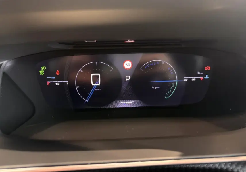 Tableau de bord numérique du Peugeot 2008 gris hybride 2025 affichant vitesse à 0 km/h et indicateurs de puissance et température.