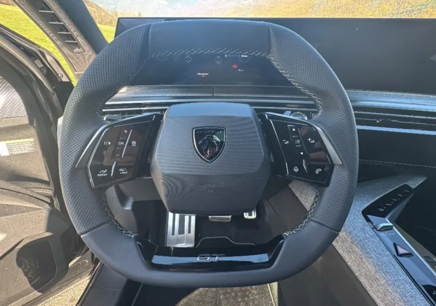 Vue rapprochée du volant cuir perforé noir avec logo Peugeot et insert GT du Peugeot 3008 New Hybrid 2025.