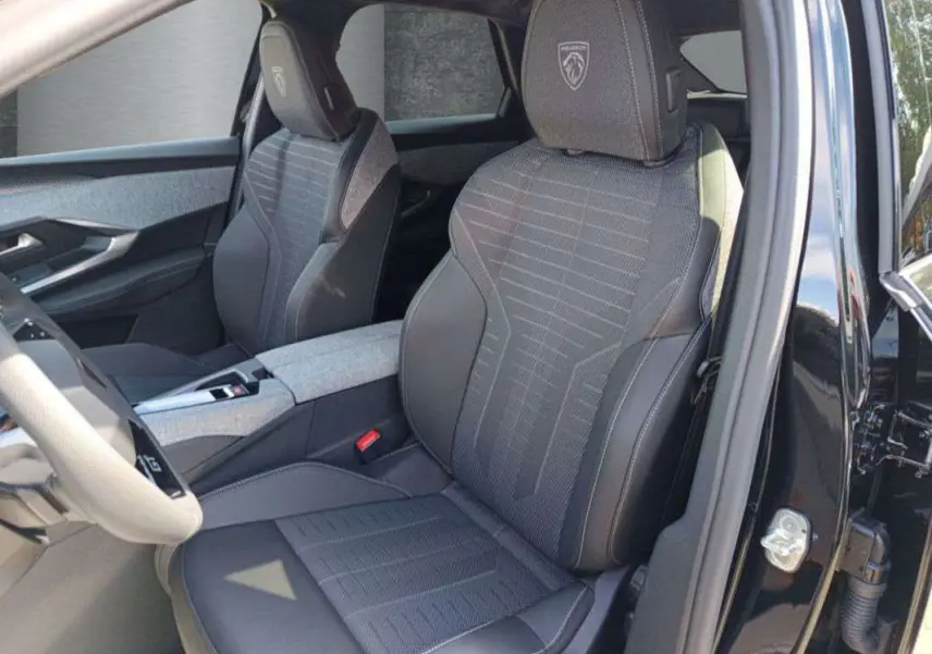Vue intérieure côté conducteur du Peugeot 3008 New Hybrid 145 GT 360 noir perla nera, sièges tissu et cuir avec logo Peugeot brodé.