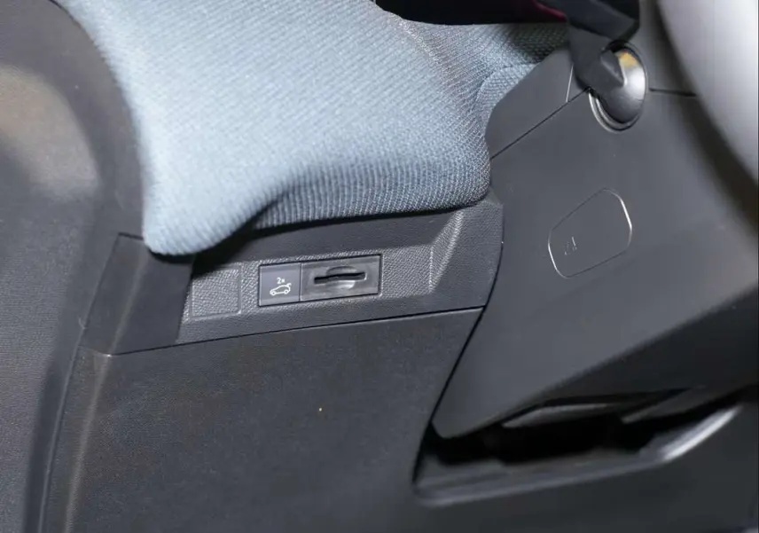 Détail intérieur montrant le bouton d'ouverture du hayon sous le tableau de bord côté conducteur du Citroën C5 Aircross blanc.