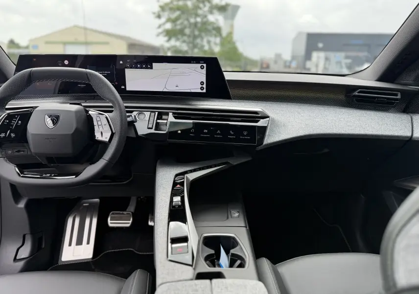 Intérieur moderne du Peugeot 3008 Hybrid 2026 vu de face, avec tableau de bord numérique et volant compact noir.