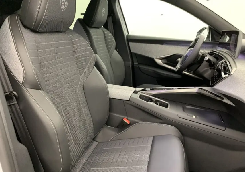 Gros plan sur la roue avant droite du Peugeot 3008 Hybrid blanc Okenite avec jante noire brillante et logo Peugeot central.