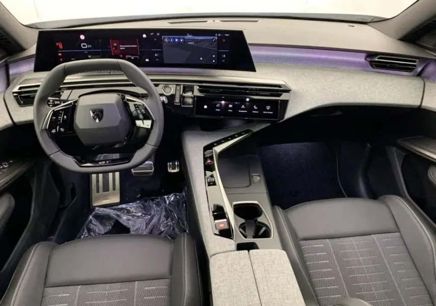 Vue intérieure rapprochée des sièges avant gris et noir du Peugeot 3008 Hybrid 2026 avec console centrale et volant partiel.