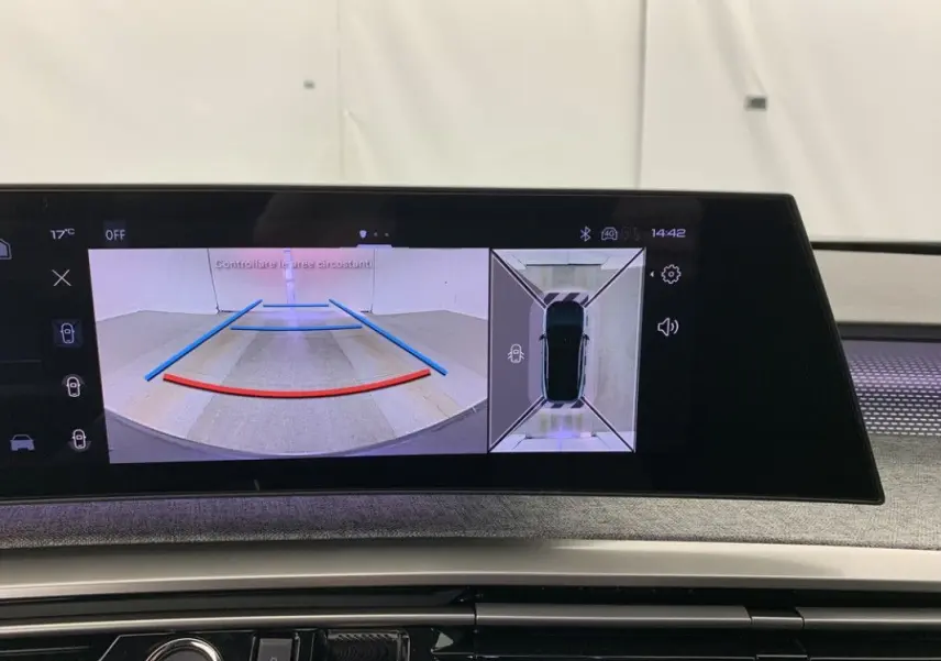 Coffre ouvert vu de l'arrière d'un Peugeot 3008 Hybrid blanc avec intérieur de coffre noir et cache-bagages relevé.