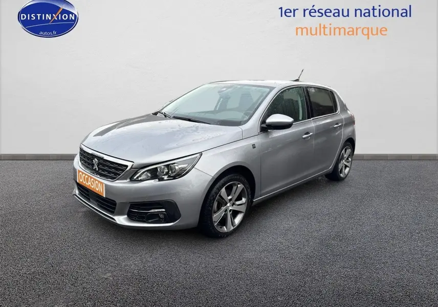 Peugeot 308 gris Artense vue 3/4 avant droit, avec jantes alliage et calandre noire brillante.