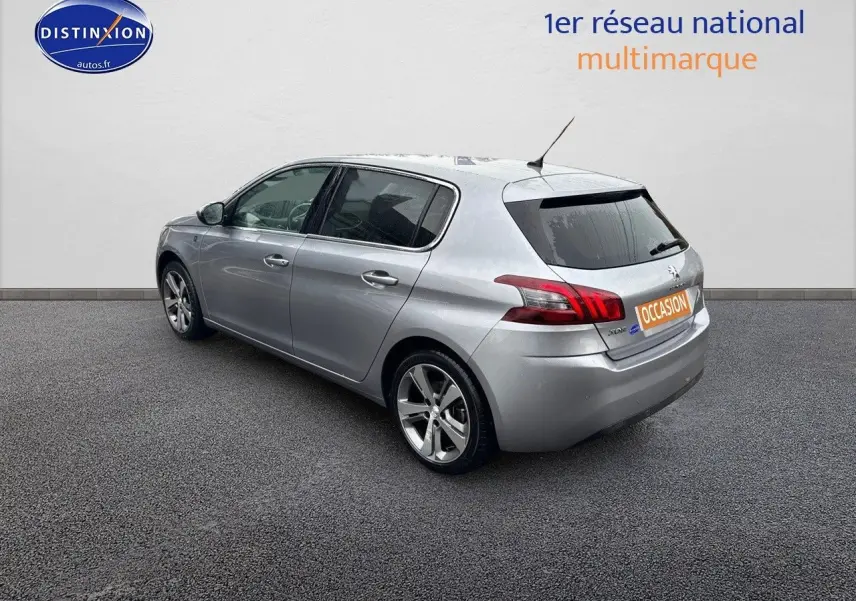 Vue 3/4 arrière droit d'une Peugeot 308 gris Artense 5 portes, avec jantes alliage et feux arrière LED distinctifs.