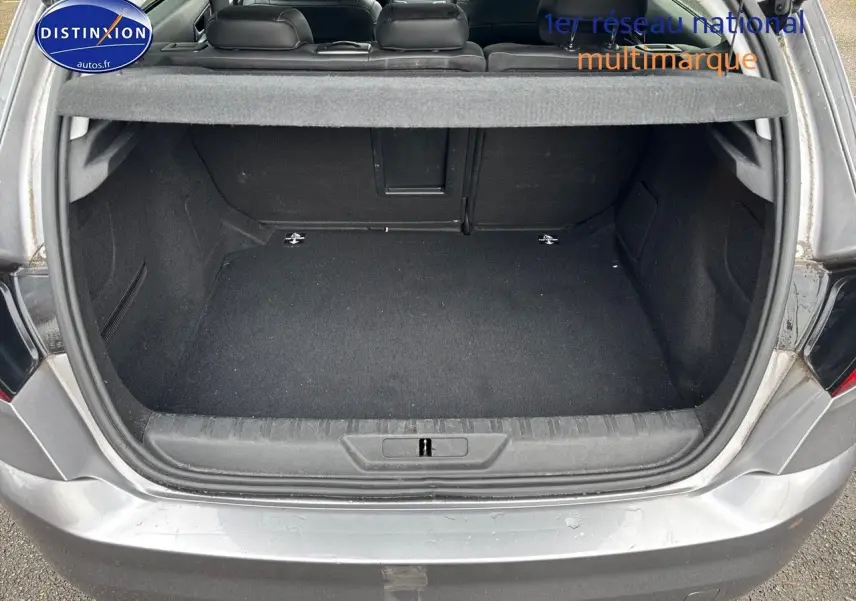 Coffre ouvert d'une Peugeot 308 gris Artense vue de l'arrière, montrant un espace de chargement propre et spacieux.