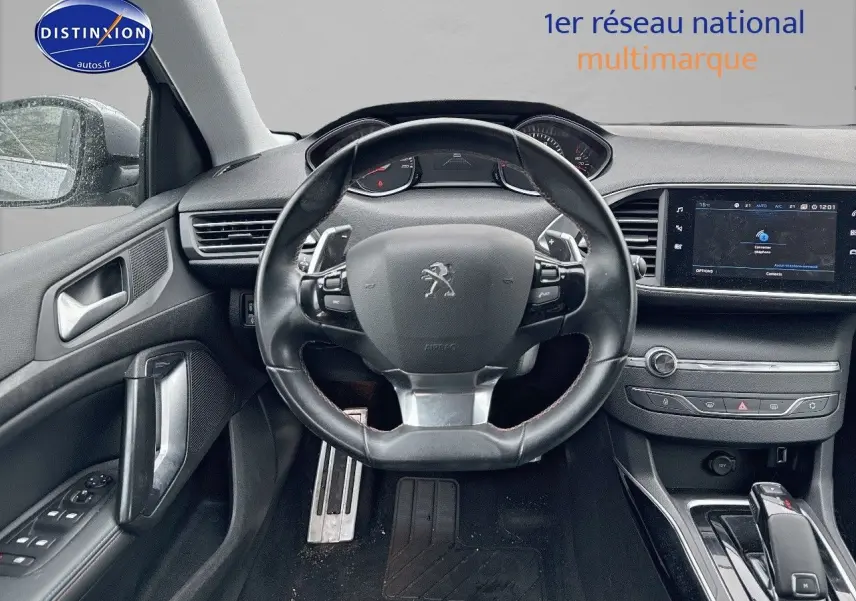 Vue intérieure centrée sur le volant cuir de la Peugeot 308 gris Artense avec tableau de bord et écran tactile.