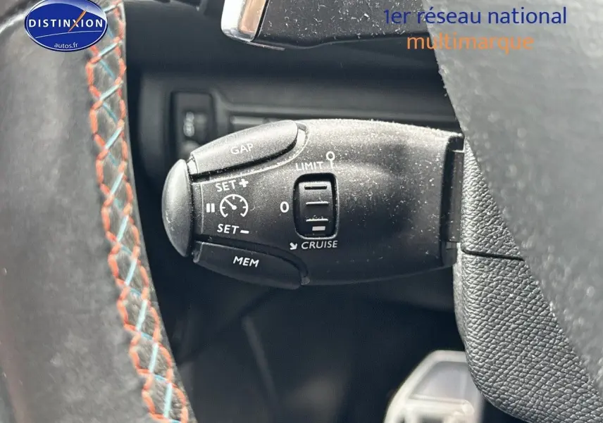 Gros plan sur la commande de régulateur de vitesse au volant d'une Peugeot 308 gris Artense de 2019.