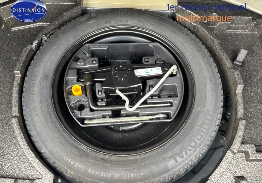 Roue de secours et outils de bord rangés dans le coffre d'une Peugeot 308 gris Artense de 2019.
