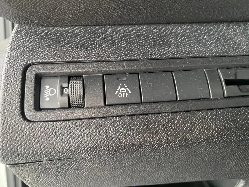 Gros plan sur les commandes de réglage des phares et d'alerte de franchissement de ligne du Peugeot 3008 blanc nacré 2023.
