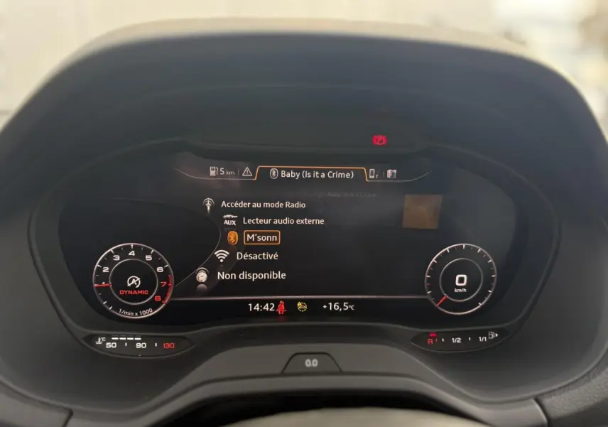 Vue rapprochée du tableau de bord numérique Audi virtual cockpit affichant les informations audio et la température extérieure.