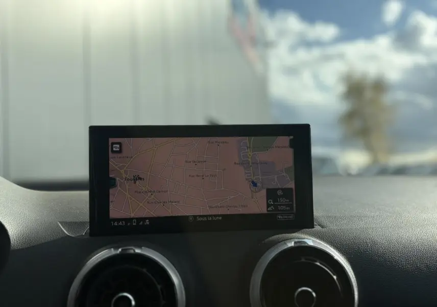 Écran de navigation central avec carte affichée, entouré de deux aérateurs ronds sur le tableau de bord noir.