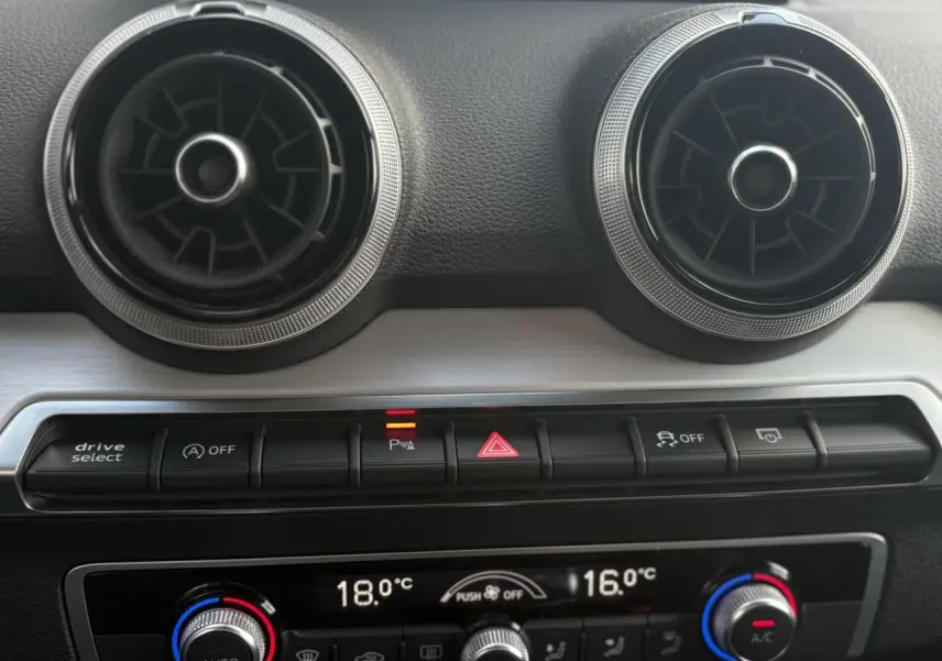 Détail du tableau de bord de l’Audi Q2 30 TFSI S-Line 2024 montrant les aérateurs ronds et commandes climatisation automatique.