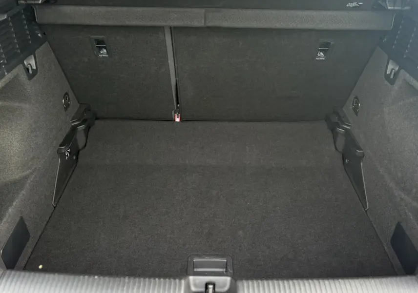 Coffre ouvert de l'Audi Q2 30 TFSI S-Line 2024, vue intérieure arrière montrant un espace de chargement noir.