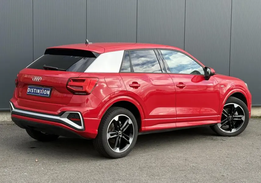 Audi Q2 30 TFSI S-Line rouge Progressif en 3/4 arrière droit, avec toit contrasté blanc et jantes noires polies.