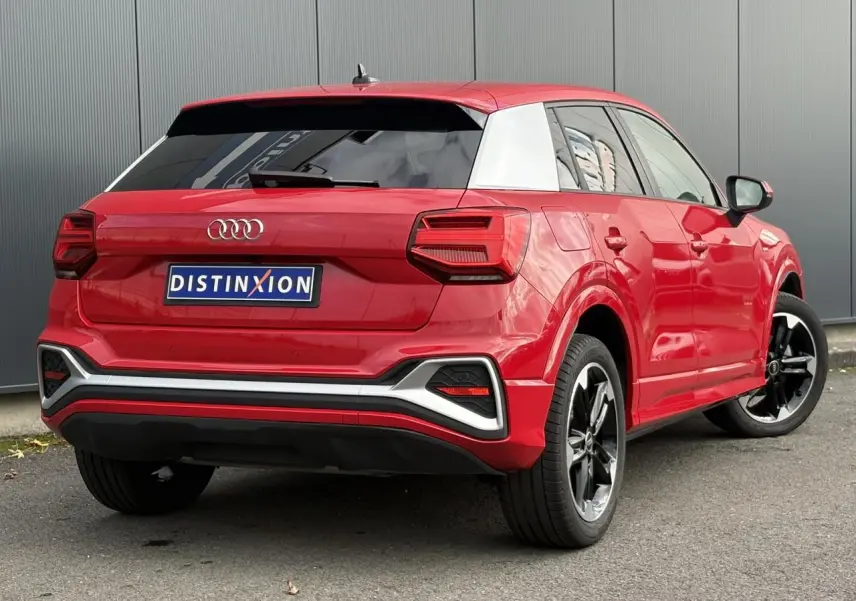 Audi Q2 30 TFSI S-Line rouge Progressif vue 3/4 arrière droit avec jantes alliage noir poli et toit contrasté blanc.