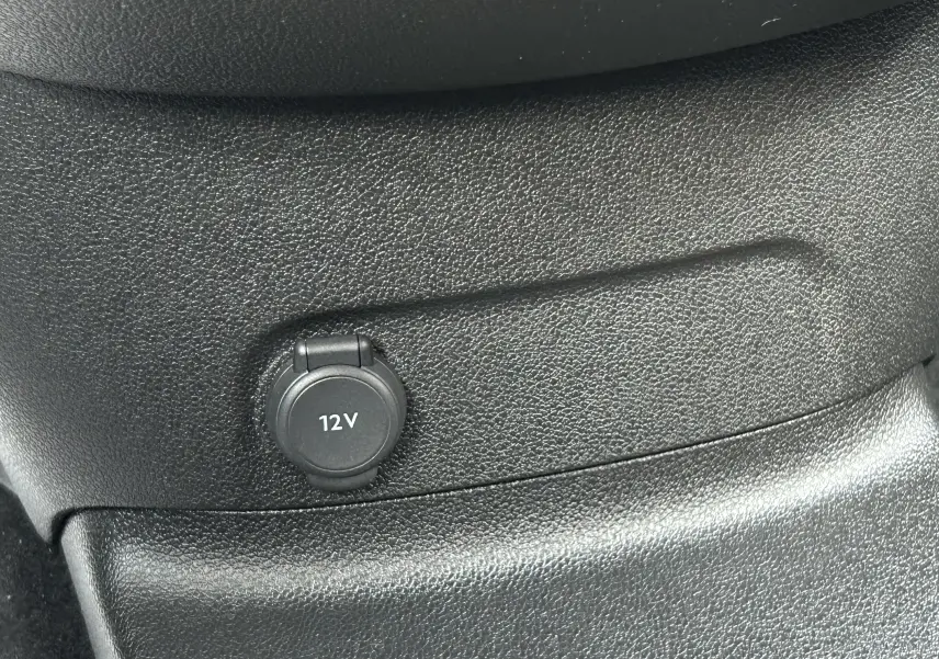 Prise 12V en gros plan sur la console intérieure noire du Peugeot Partner Fourgon blanc 2025.