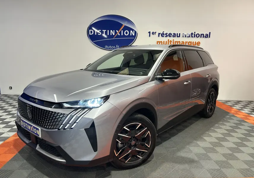 Peugeot 5008 gris Artense en 3/4 avant droit, avec phares LED allumés et jantes noires brillantes.