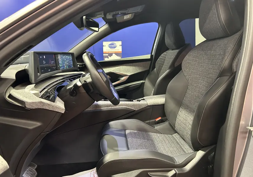 Vue intérieure côté conducteur du Peugeot 5008 gris Artense 2025, avec sièges bi-matière et tableau de bord numérique.