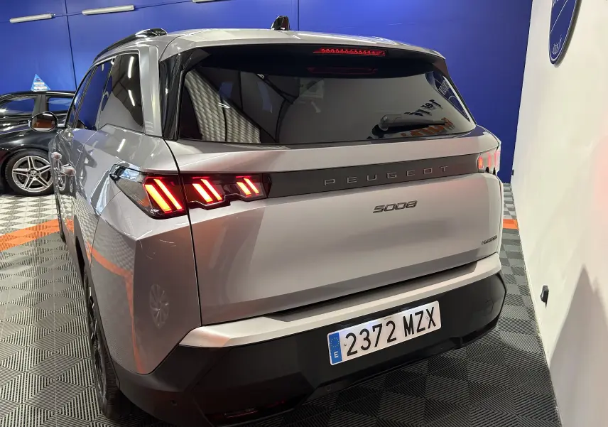 Vue 3/4 arrière d’un Peugeot 5008 gris Artense avec feux arrière allumés dans un showroom.