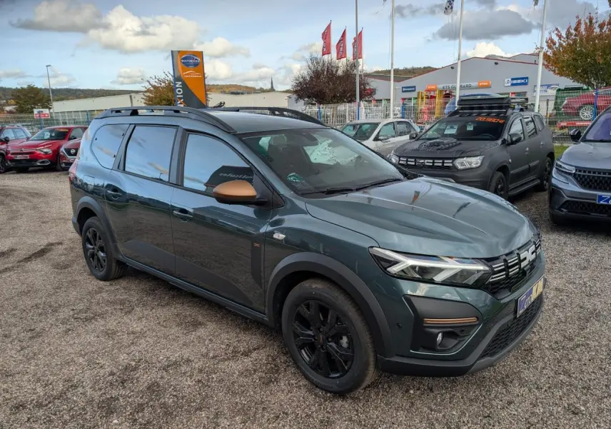 Dacia Jogger vert métallisé en vue 3/4 avant droit avec rétroviseurs brun cuivré et jantes noires.