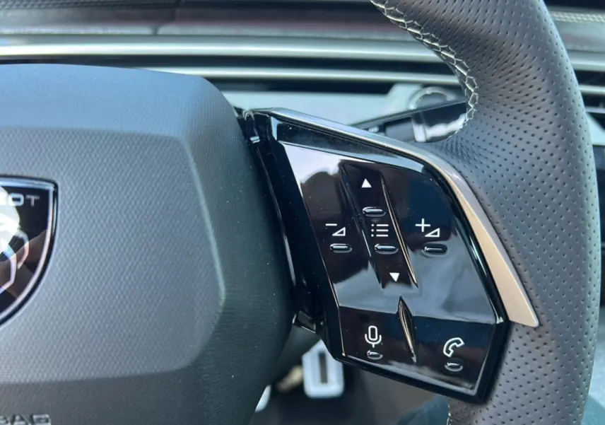 Gros plan sur la partie droite du volant cuir perforé du Peugeot 3008 gris titane, avec commandes multifonctions.
