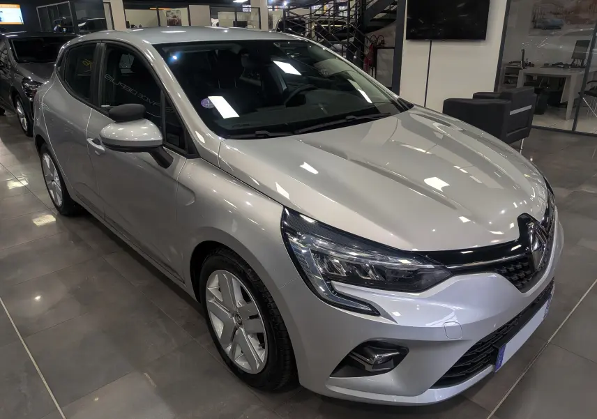 Vue 3/4 avant gauche d'une Renault Clio V gris platine avec feux LED et jantes alliage en showroom.