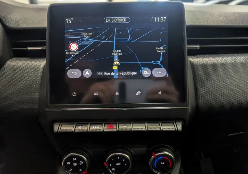 Écran tactile central avec navigation GPS et commandes de climatisation dans Renault Clio V TCe 90 Gris Platine, vue intérieure frontale.