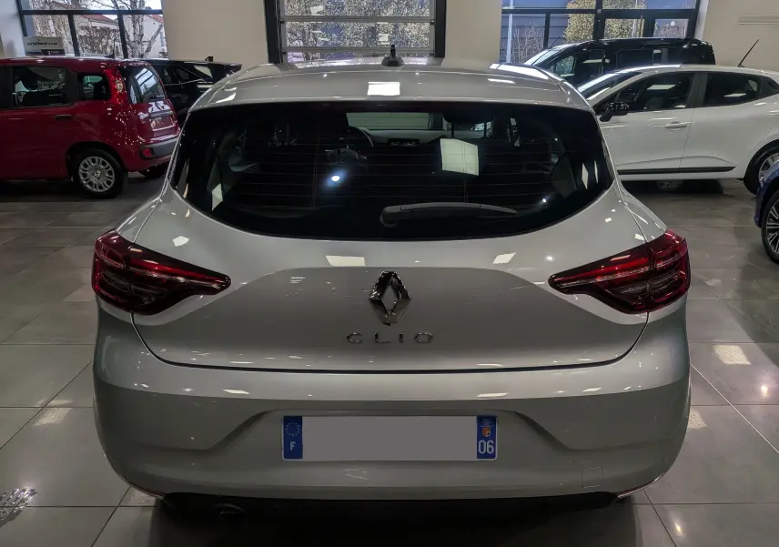 Vue arrière d'une Renault Clio V gris platine en intérieur, avec feux arrière LED et logo Renault bien visibles.