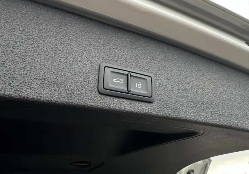 Gros plan sur les boutons d'ouverture et de verrouillage du hayon électrique de l'Audi Q2 argent rosé.