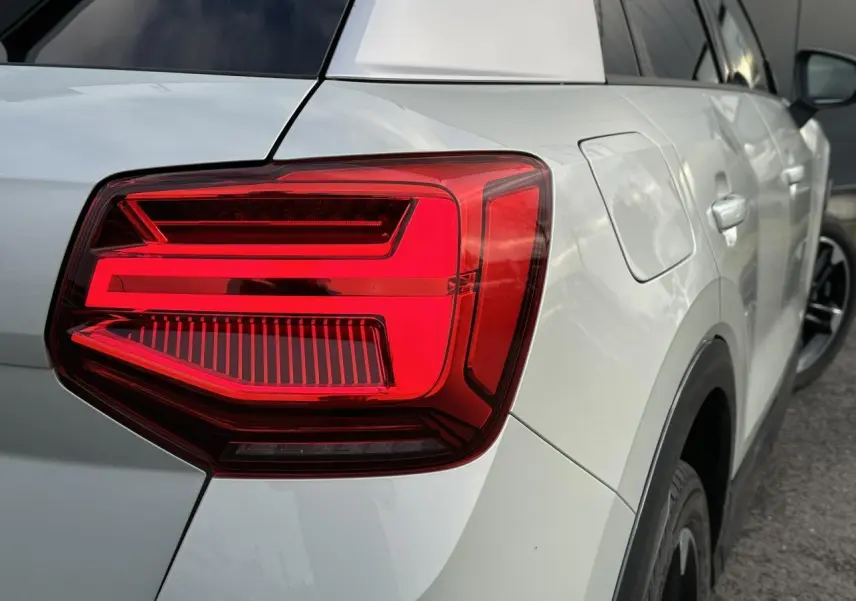 Gros plan sur le feu arrière droit d’un Audi Q2 30 TFSI S-Line argent rosé avec jante noire et détails noirs.
