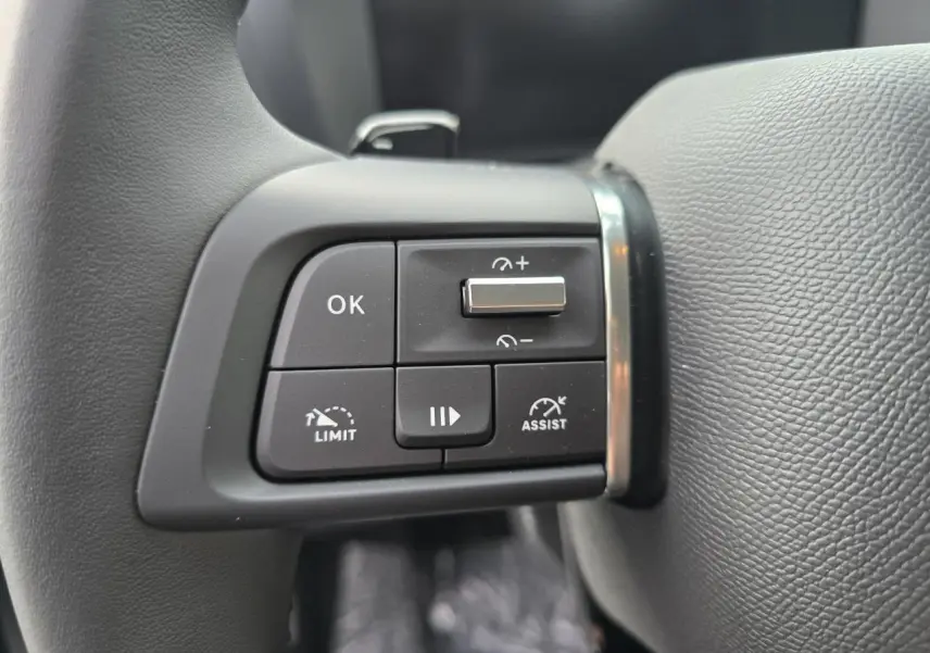 Gros plan sur les commandes de régulateur de vitesse au volant cuir noir du Citroën C4 hybride 2025.