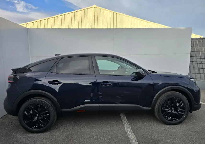 Profil côté gauche de la Citroën C4 III hybride 2025 en bleu eclipse avec toit noir et jantes noires.